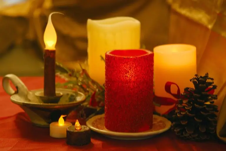 A warm and cozy holiday scene with glowing candles and pine cones on a festive red backdrop.